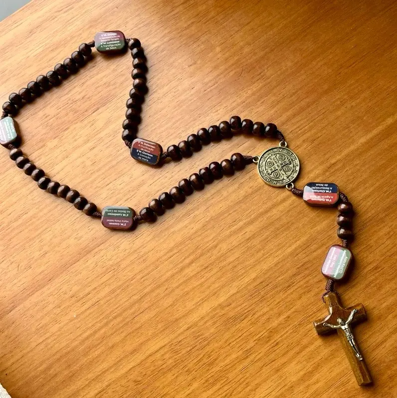 Terço completo estendido sobre mesa de madeira mostrando todas as contas e crucifixo